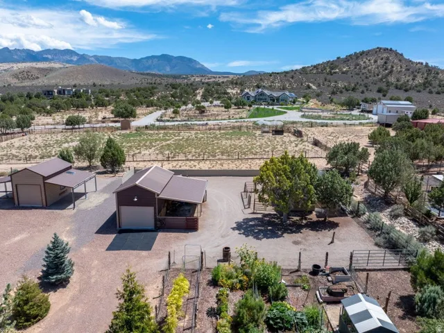 Multiple outbuildings with attached carports, fenced garden area, and a large gravel driveway