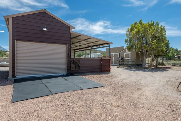 Detached structure with roll-up door, covered extension, and metal fencing