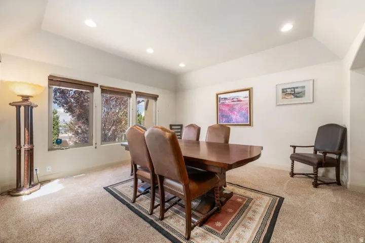 Vaulted ceiling with recessed lighting, light-toned walls, and carpet flooring