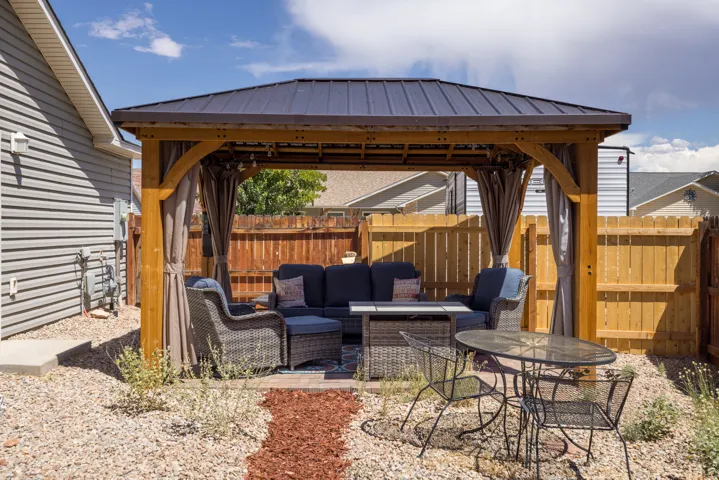 Wood-frame gazebo with a metal roof and privacy drapes