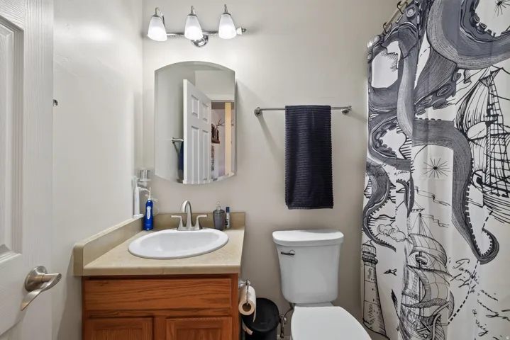 Bathroom featuring a wood-finish vanity with an undermount circular sink, brushed nickel faucet, and arched mirror