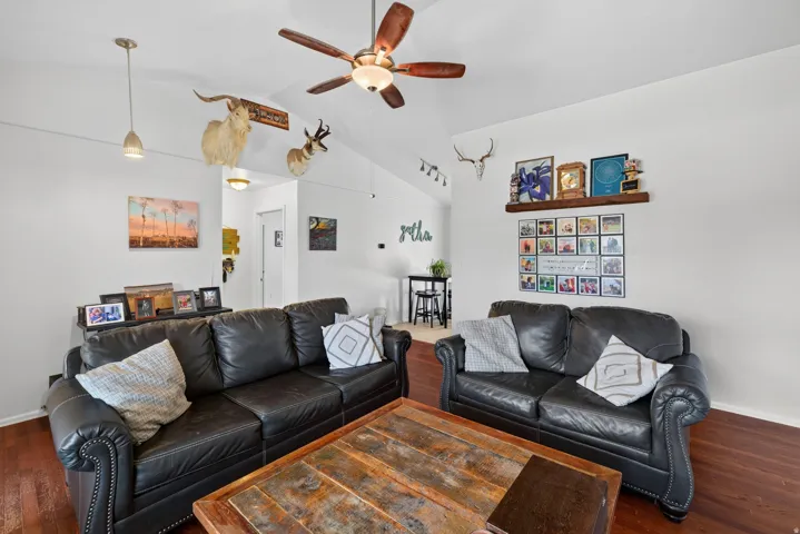 Vaulted ceiling with a ceiling fan, hardwood-finish flooring, and track lighting