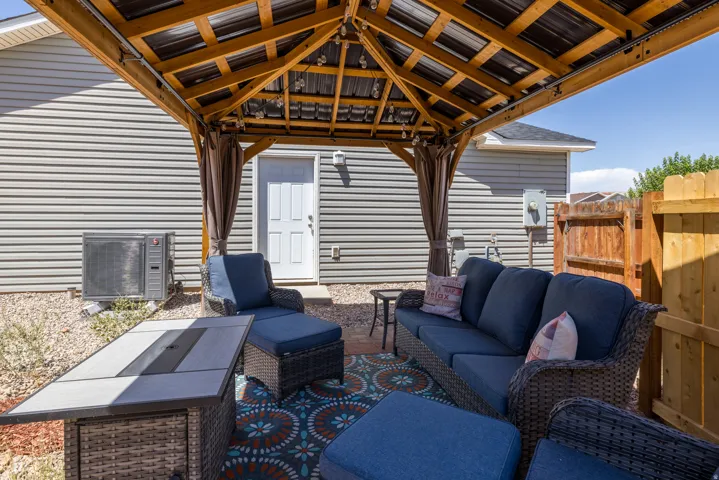 Outdoor living area featuring a wood-framed pergola with a metal roof, gravel ground cover, a white exterior door, and horizontal siding
