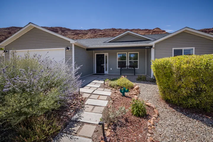 Siding exterior, asphalt shingle roof, attached garage, concrete pathway, and desert landscaping
