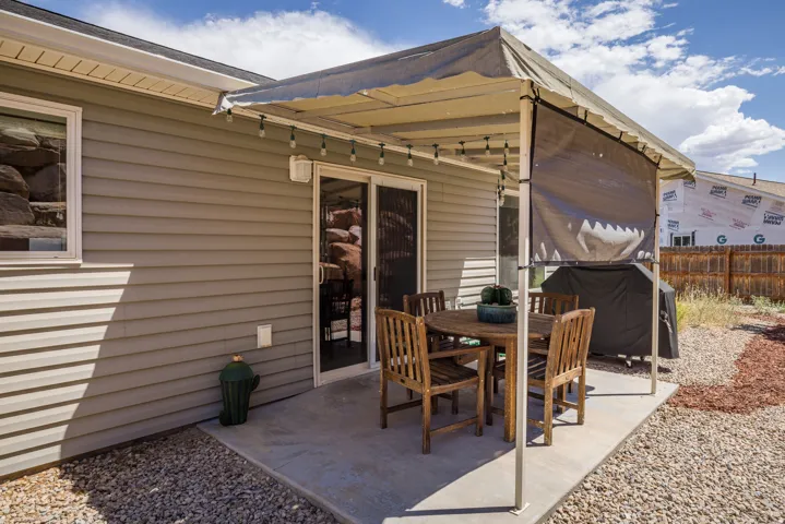 Concrete patio area with a covered awning, durable siding, and sliding glass door access