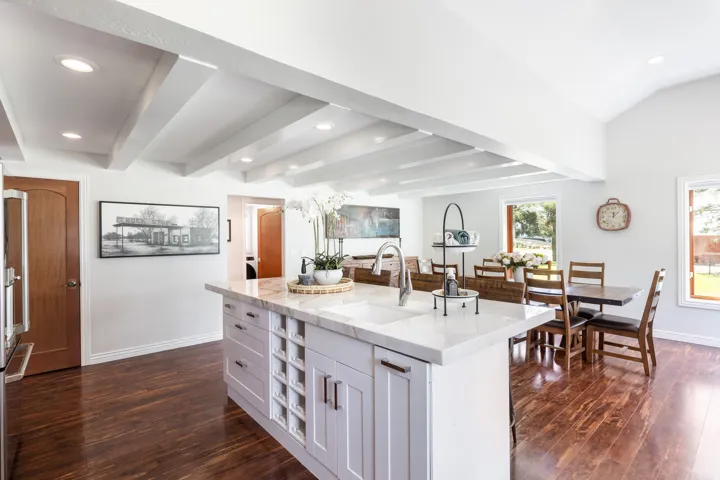 Kitchen island with an undermount sink, a gooseneck faucet, and white cabinetry