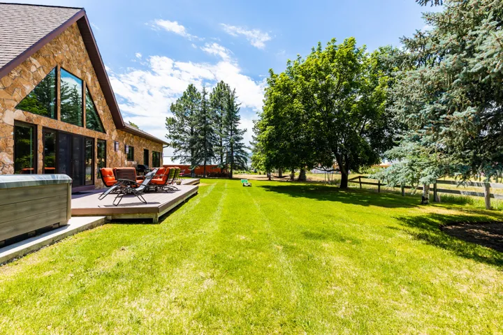 Stone exterior residence featuring an elevated outdoor deck, large picture windows, and a prominent gable roofline