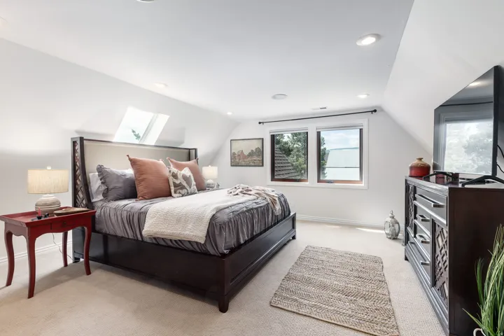 Sloped ceiling room featuring recessed lighting, a skylight, and two windows