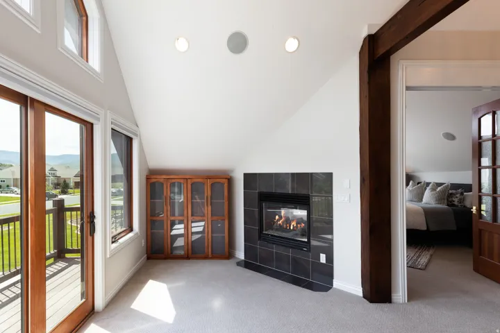 Integrated fireplace with black tile surround, wood-finish beam, and recessed lighting