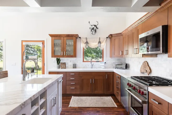 Kitchen featuring vaulted ceilings with exposed beams, wood-finish flooring, wood cabinetry, white countertops, and stainless steel appliances
