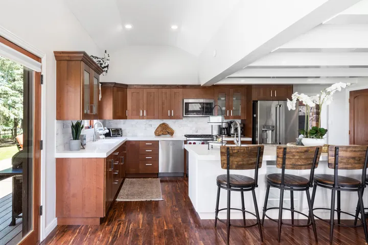 Kitchen featuring wood-finish cabinetry, stainless steel appliances, white countertops, and a white tile backsplash