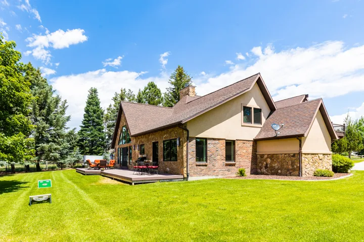 Expansive green lawn with mature trees and a multi-level deck