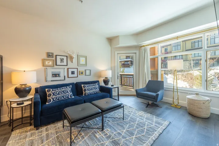 Expansive windows with exterior views, glass paneled door leading to a balcony, and dark wood-finish flooring