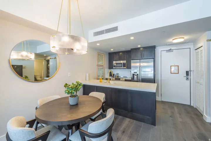 Contemporary kitchen with dark wood-finish cabinetry, stainless steel appliances, and a light-toned countertop