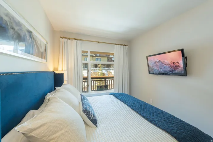 Recessed lighting, wall-mounted television, and a window with balcony access