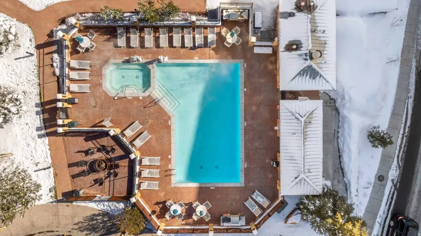 Outdoor swimming pool with integrated spa and surrounding paver patio