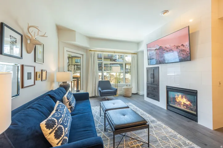 Wood-finish flooring, built-in fireplace, white tiled accent wall, and recessed lighting