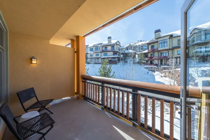 Private balcony with exterior wall sconce, concrete flooring, and wood-finish railing