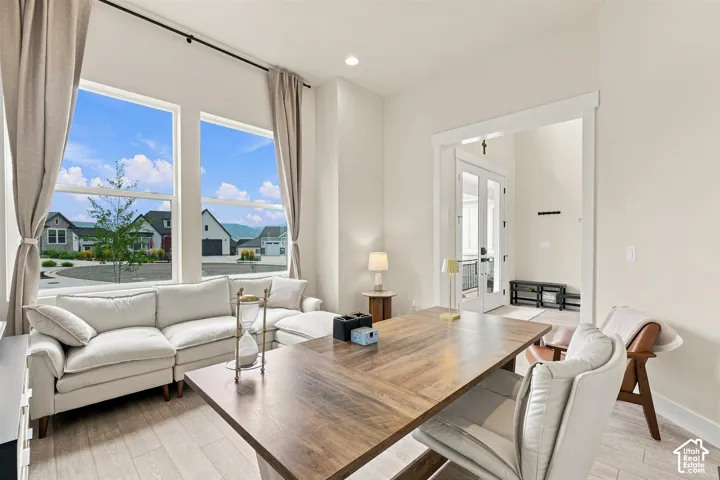 Also could be a formal living room. Tall windows with neutral drapes, high ceilings, and wood like-finish flooring
