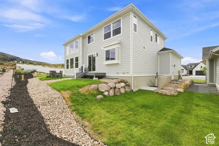 Walk  out basement door. Light gray siding exterior with multiple windows, a large deck, and a bay window