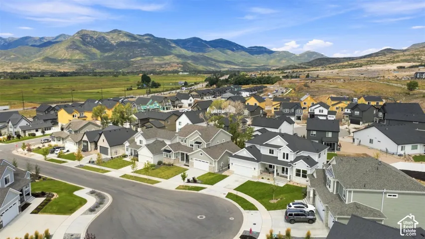 Residential community with a variety of architectural styles, manicured lawns, paved streets, and a prominent mountainous backdrop