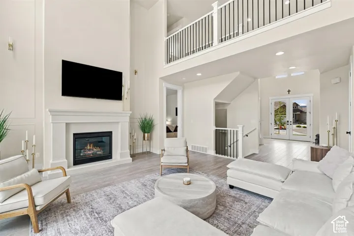 Two-story living area featuring a fireplace with a decorative mantel, and a second-story interior balcony with black metal balusters