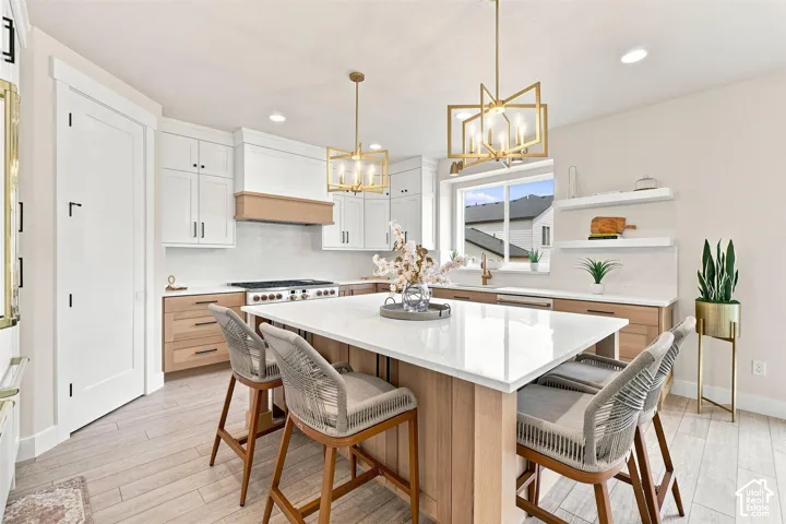 Spacious kitchen featuring an expansive central island with counter seating, a stainless steel range, and a coordinating range hood. Quartz Countertops and built in island microwave