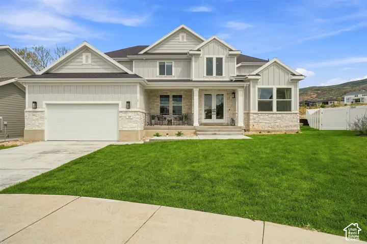 Front exterior featuring light-colored siding, stone accents, a covered front porch, and an attached garage. Cul-de-sac location