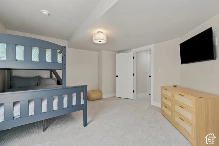 Recessed ceiling, neutral wall tones, white trim, wall-mounted television, and light-colored carpet