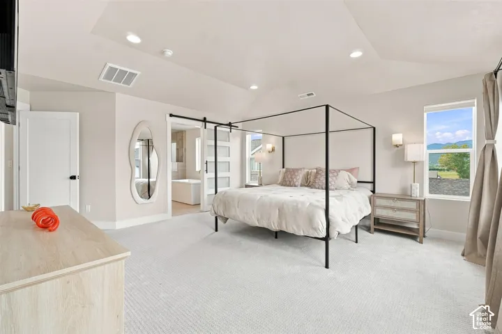 Spacious Primary bedroom. Tray ceiling, recessed lighting, carpet flooring, window with natural scenery, barn door into master bath.