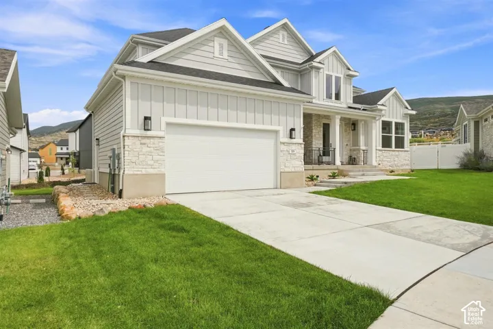 Contemporary exterior with light siding, stone accents, a covered porch, an integrated garage, and  concrete driveway