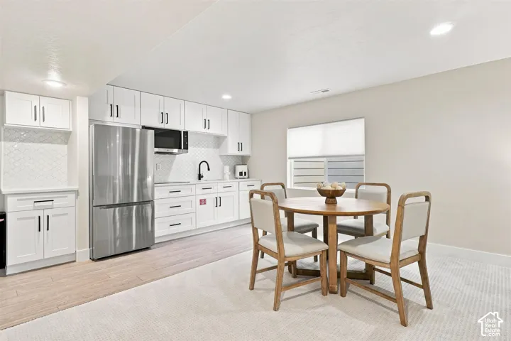 Full kitchen with white cabinetry, stainless steel appliances, and white tile backsplash