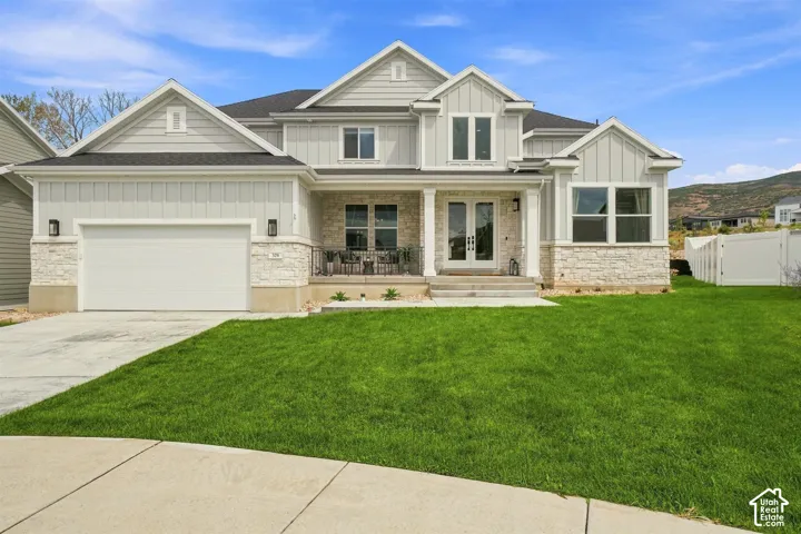 Contemporary exterior featuring light-colored siding, stone veneer accents, and a covered front porch
