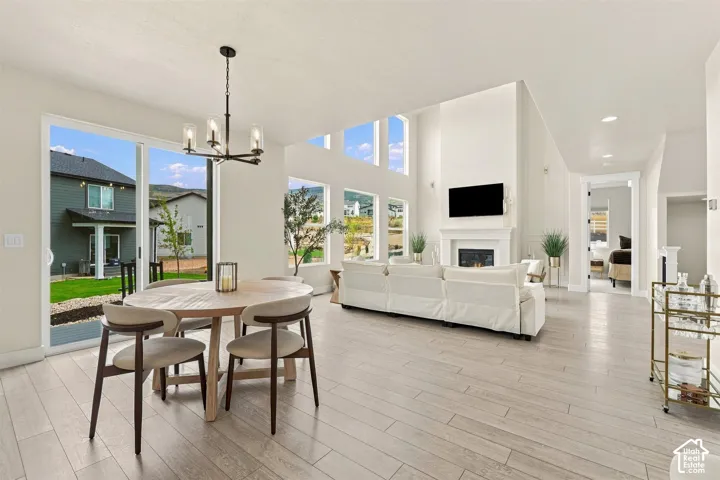 Open concept living space featuring high ceilings, wood like-finish flooring, Two story fireplace with mantel, and 2 Story windows