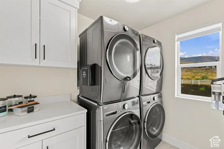 Upper laundry room with dual washer & dryer. White shaker cabinetry with dark hardware