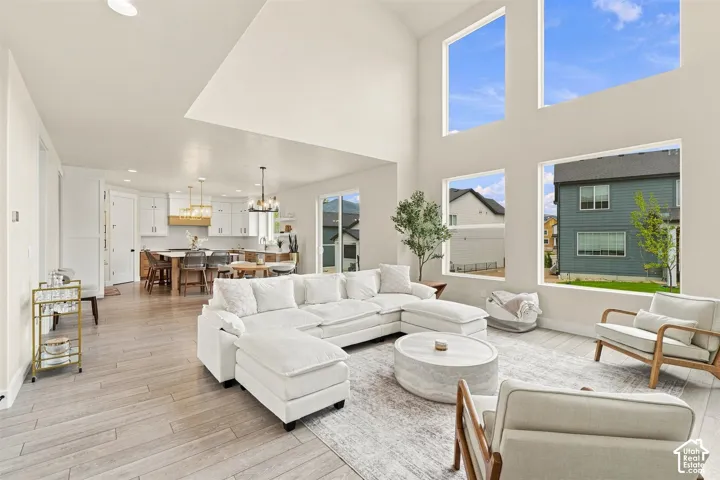 Expansive living area with vaulted ceilings, two story windows, and wood-finish flooring