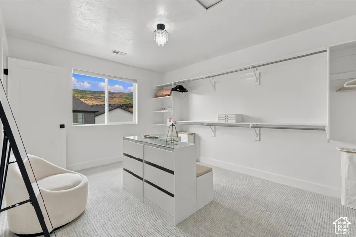 Primary closet. Spacious walk-in closet featuring built-in shelving, hanging rods, and a central dresser island with a glass top!