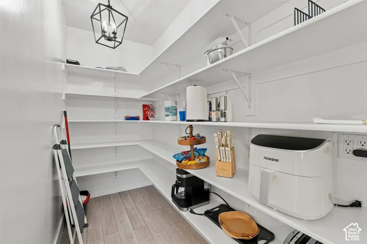 Walk-in pantry featuring white shelving, wood-finish flooring, and a contemporary fun ceiling fixtures