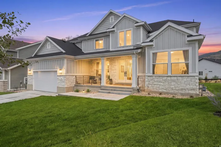 Contemporary gray exterior with stone accents, a covered front porch, and a two-car garage
