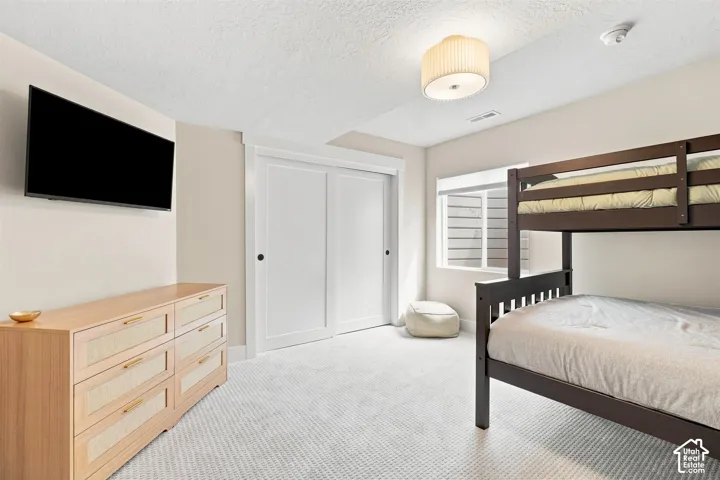 Light-colored carpeted flooring, spacious bedroom and closet.