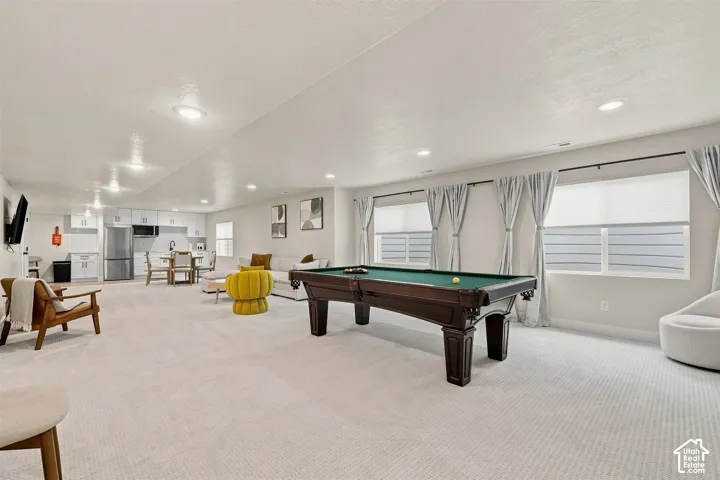 Expansive recreational room featuring polished light-neutral carpeting throughout, recessed ceiling lighting, and large multi-pane windows with operable shutters