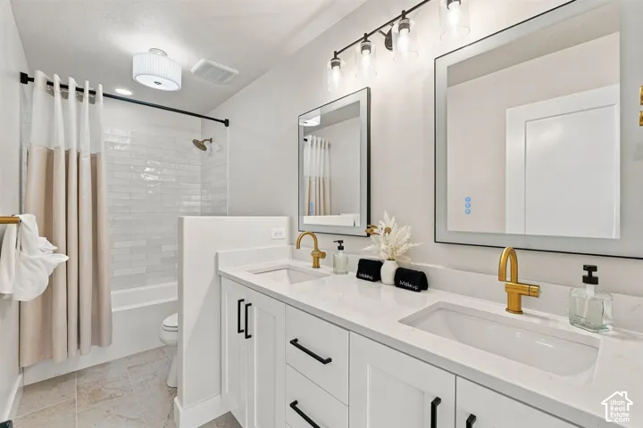 Full bath with Dual vanity with white cabinetry and quartz countertops