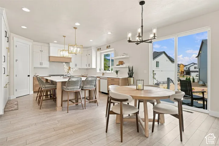 Open-concept kitchen and semi formal dining area featuring white shaker cabinetry, wood like-finish flooring, a large kitchen island with counter seating, and glass sliding doors out to the back yard