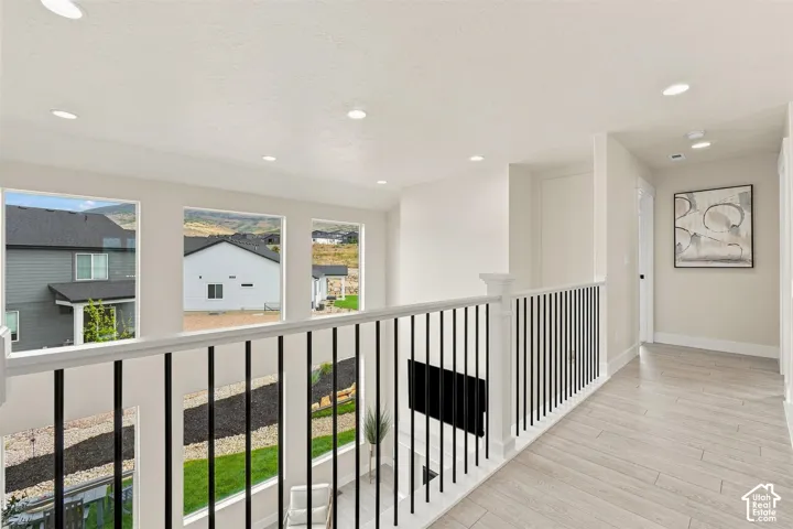 Recessed lighting illuminates the upper-level hallway featuring light wood-finish flooring. Overlooks great room and entry way