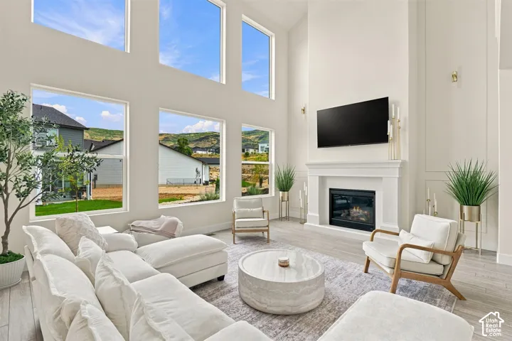 Soaring ceilings with transom windows, gas fireplace with a classic mantel, wood like-finish flooring, and built-in wall sconces