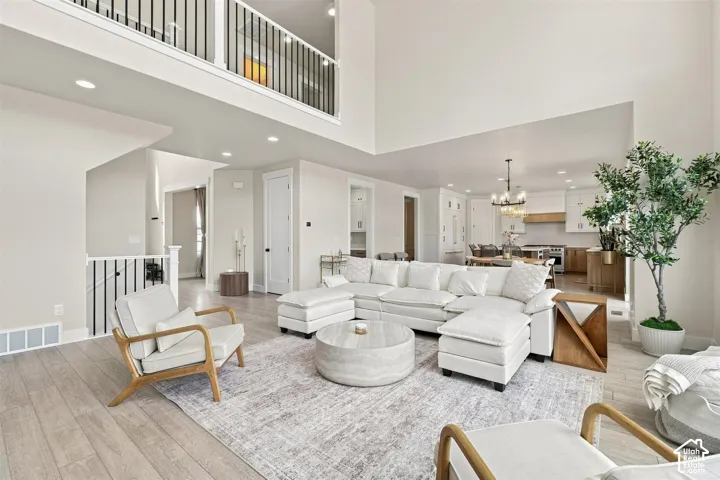 Vaulted ceilings with an open concept designed great room, featuring wood-like finish flooring and a second-story balcony with metal railings