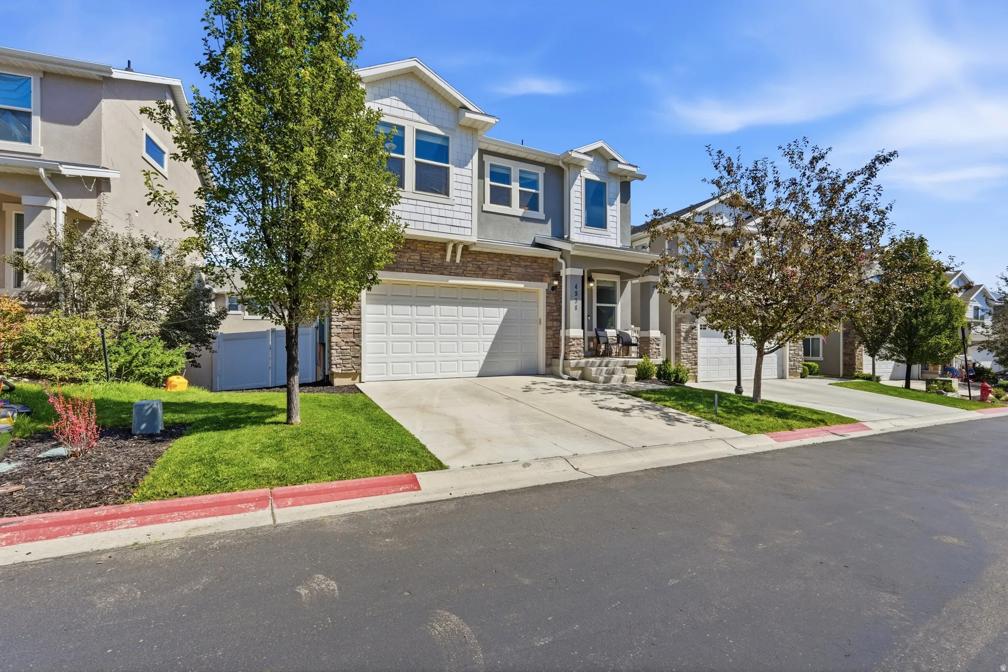 Multi-story residence featuring a two-car garage, stone and siding exterior, and a covered front porch