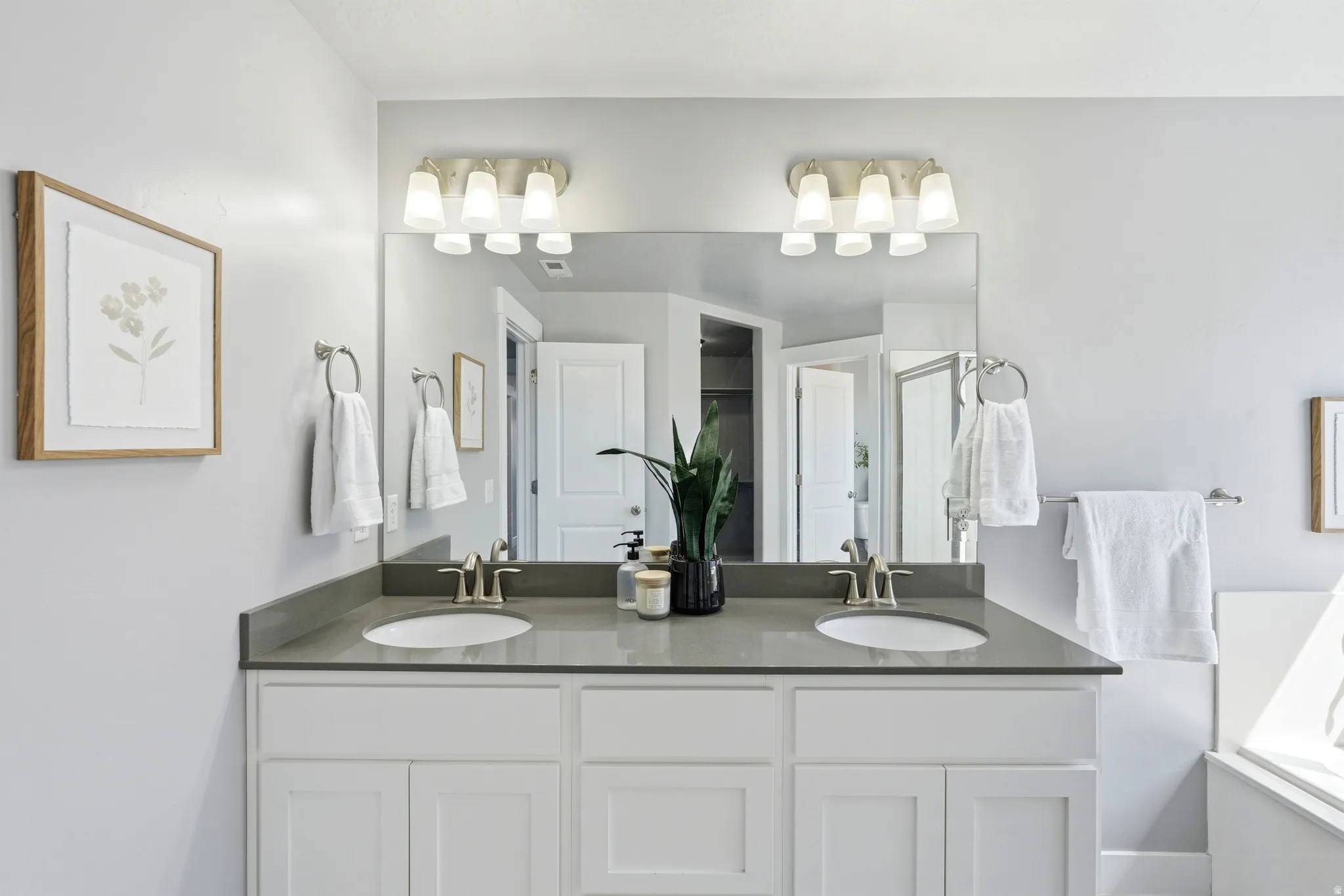 Dual vanity with white cabinetry, undermount sinks, and a dark countertop