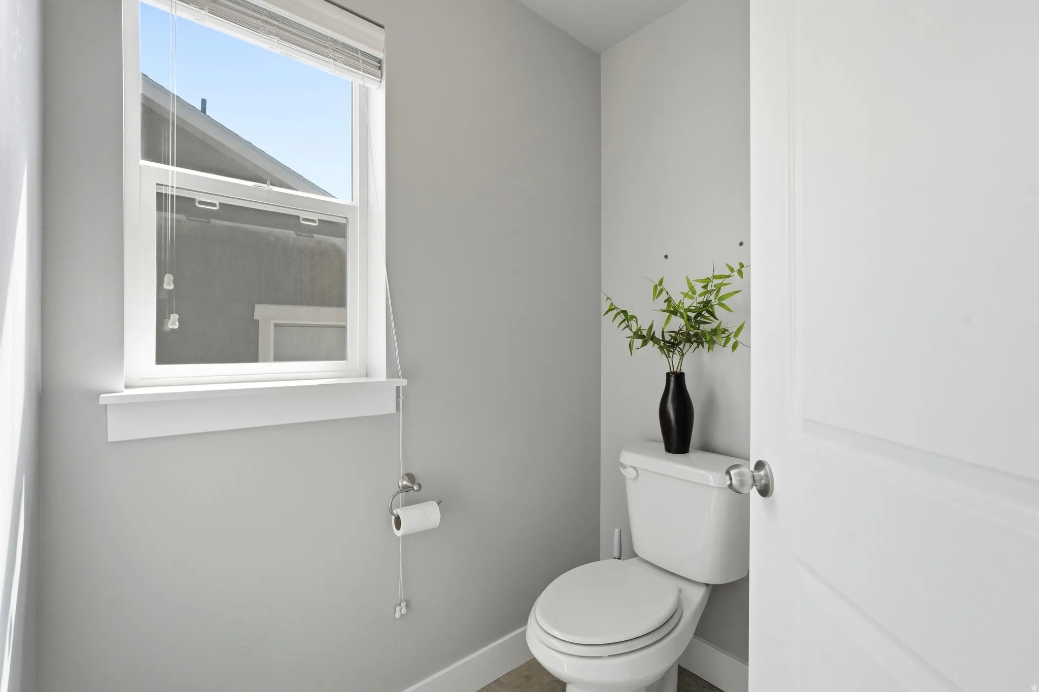 Recessed toilet with a white tank and bowl, featuring a single-pane window with white trim
