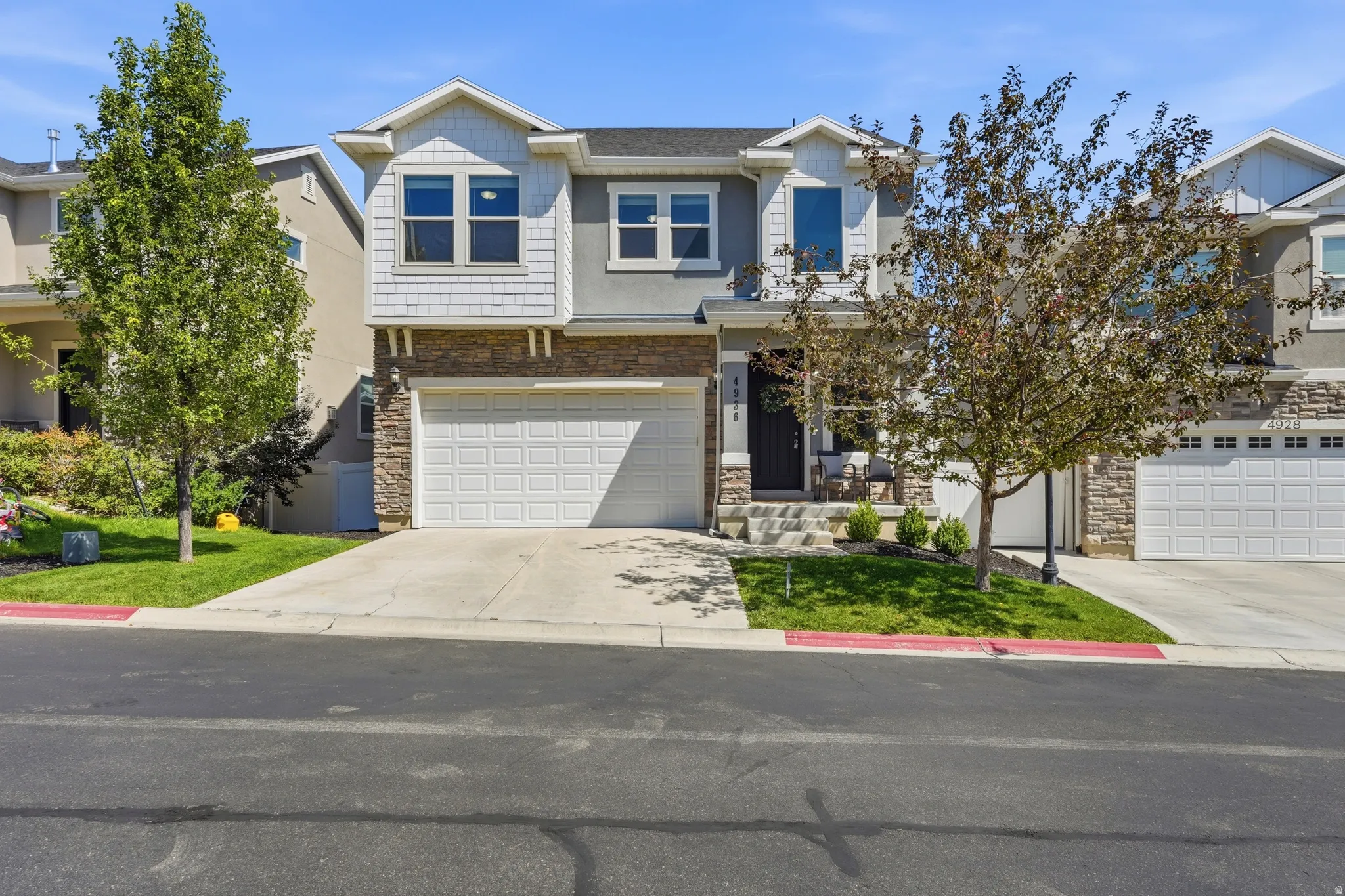 Multi-story residence featuring a two-car garage, stone veneer accents, and partial siding